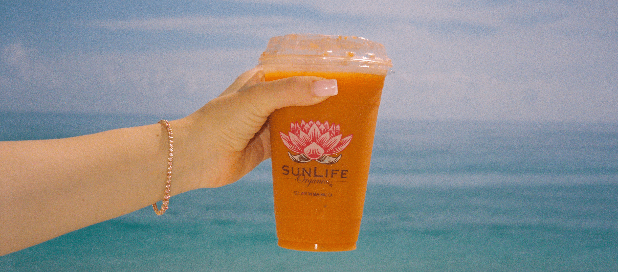 hand holding orange sunlife smoothie